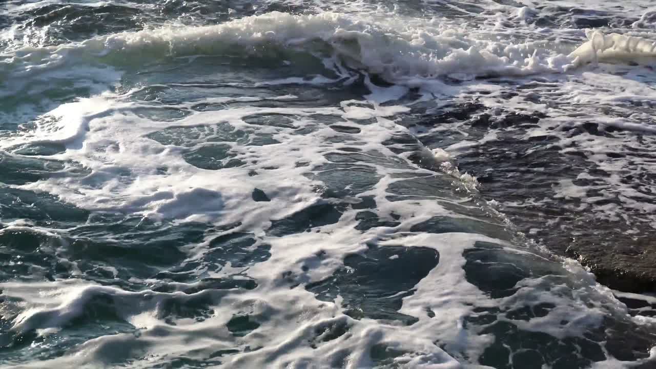 A wave caught as it breaks over coastal rocks